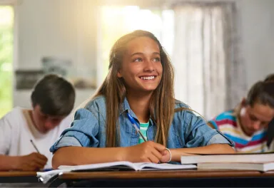 Lachend meisje in de klas met huiswerk voor zich